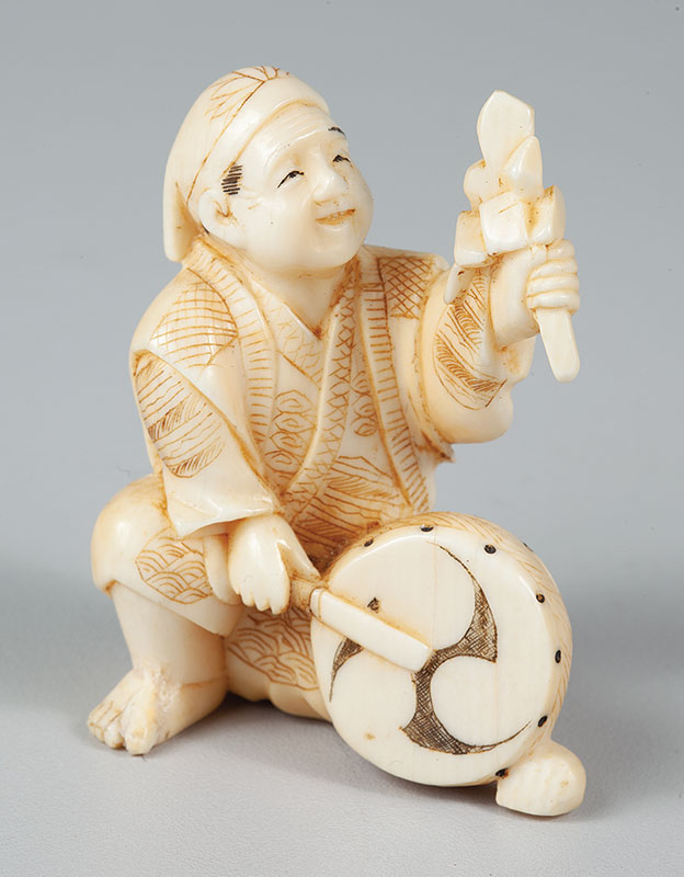 NETSUKE - Em marfim representando figura de músico com tambor - medindo 6 cm de altura. - Japão - Séc.XX.